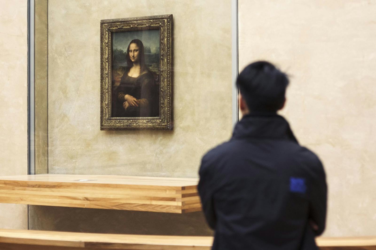 Vizitator contemplând Mona Lisa la Muzeul Louvre